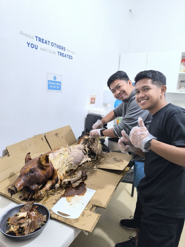 Team members serving a shared lechon lunch in the office