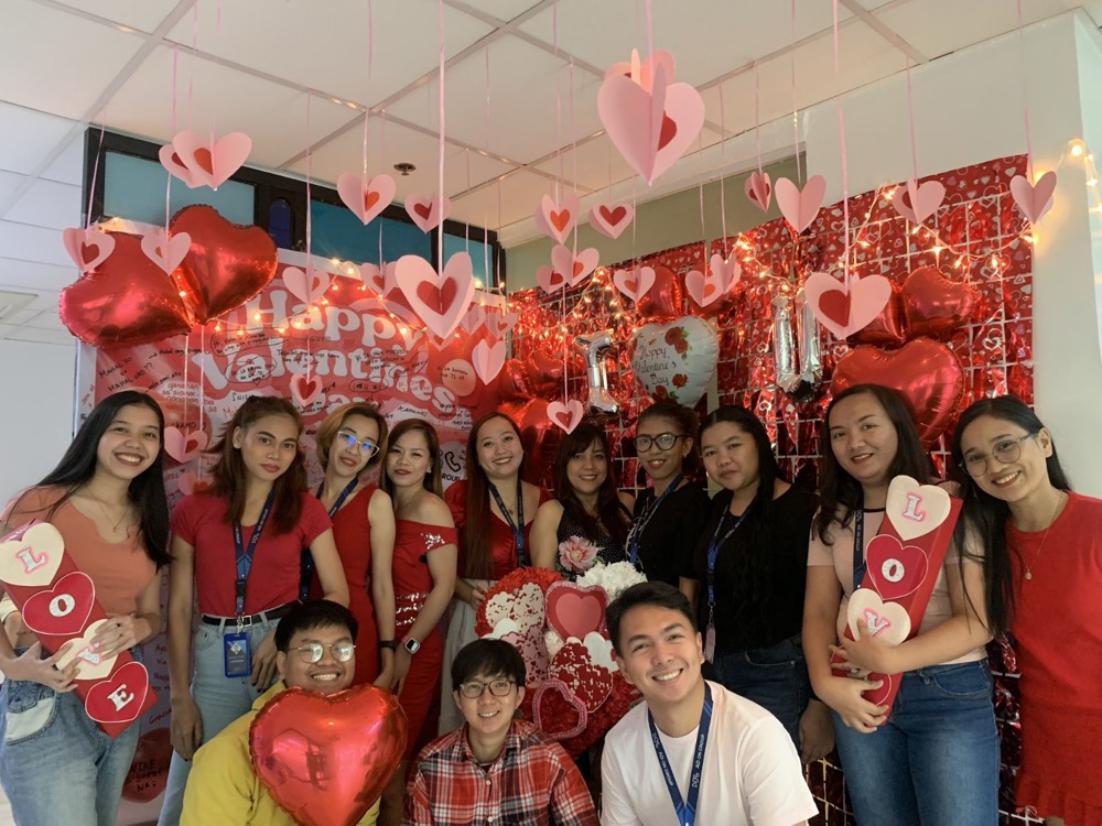 Staff holding heart balloons at an office celebration